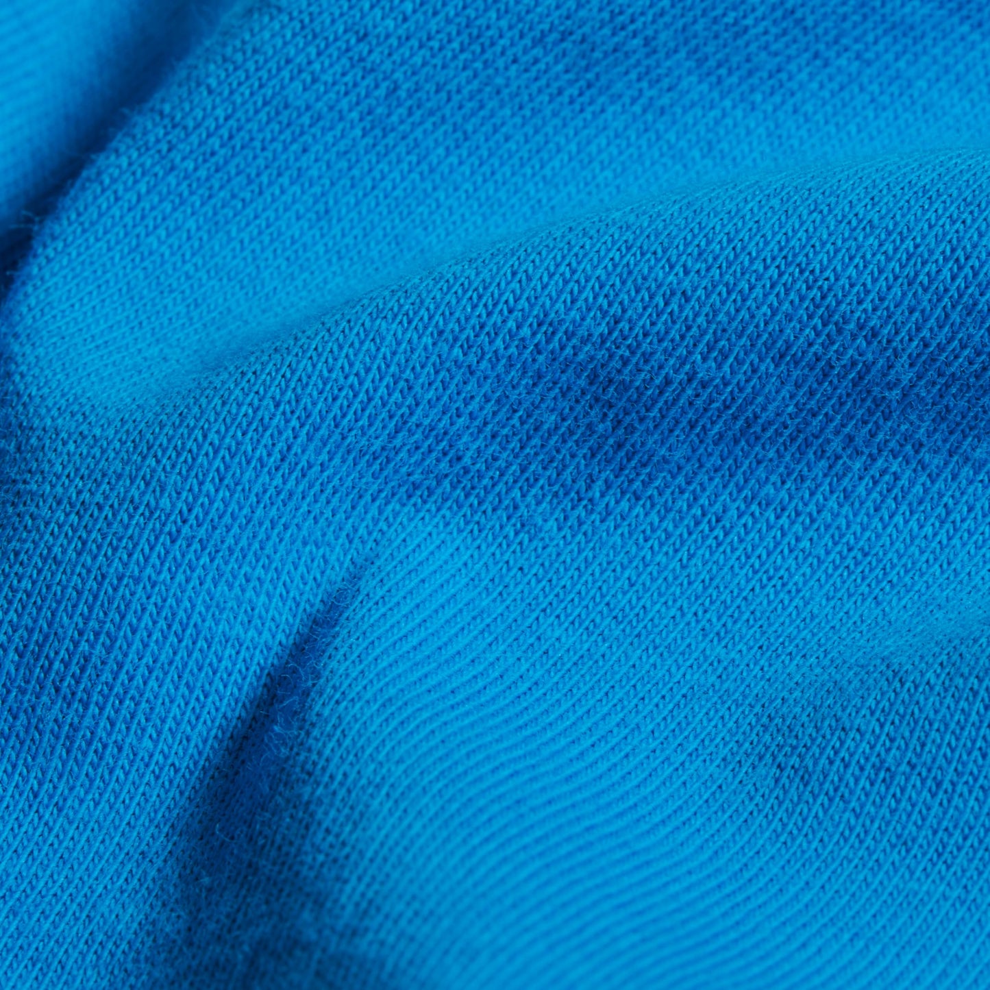 Bright blue knit T-shirt fabric close-up with fine textured weave