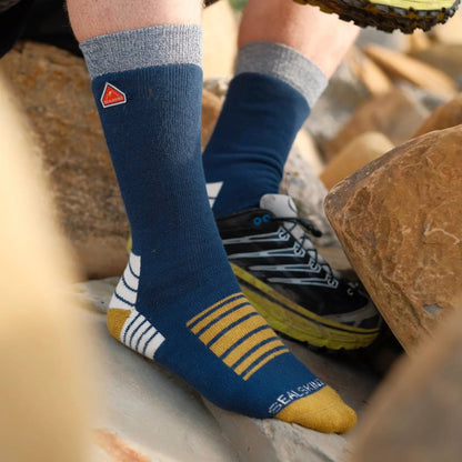 Mid-length hiking socks in navy with yellow striped panels and cream heel; worn shoes