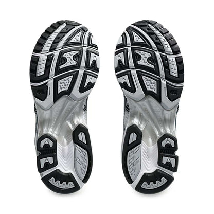 Rear soles of white and black running trainers with patterned rubber tread