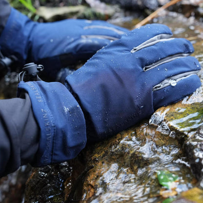 Blue waterproof lightweight gauntlet gloves resting outdoors on a rock surface