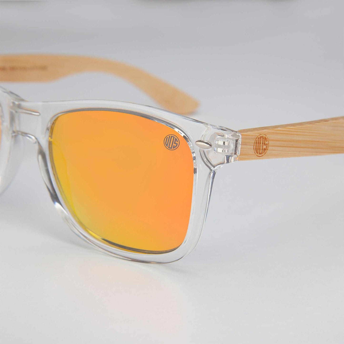Clear sunglasses close-up with orange mirrored lenses and bamboo-look arms