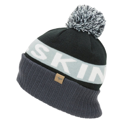 Black knit bobble beanie with light grey stripe reading "SK" and a tan leather logo patch
