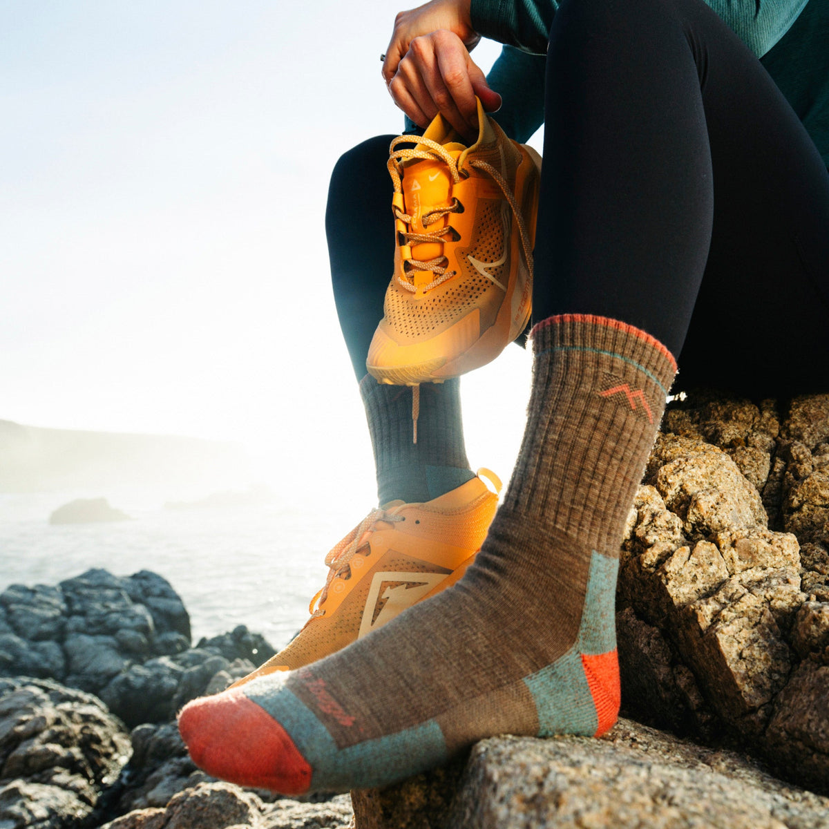 Brown micro crew hiking socks with blue and red accents, on rocky terrain