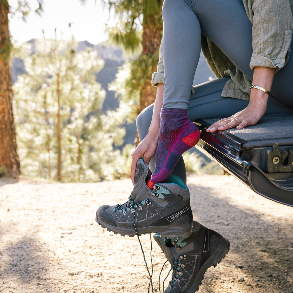 Pair of ankle hiking merino socks, blue with red toe and heel, on legs