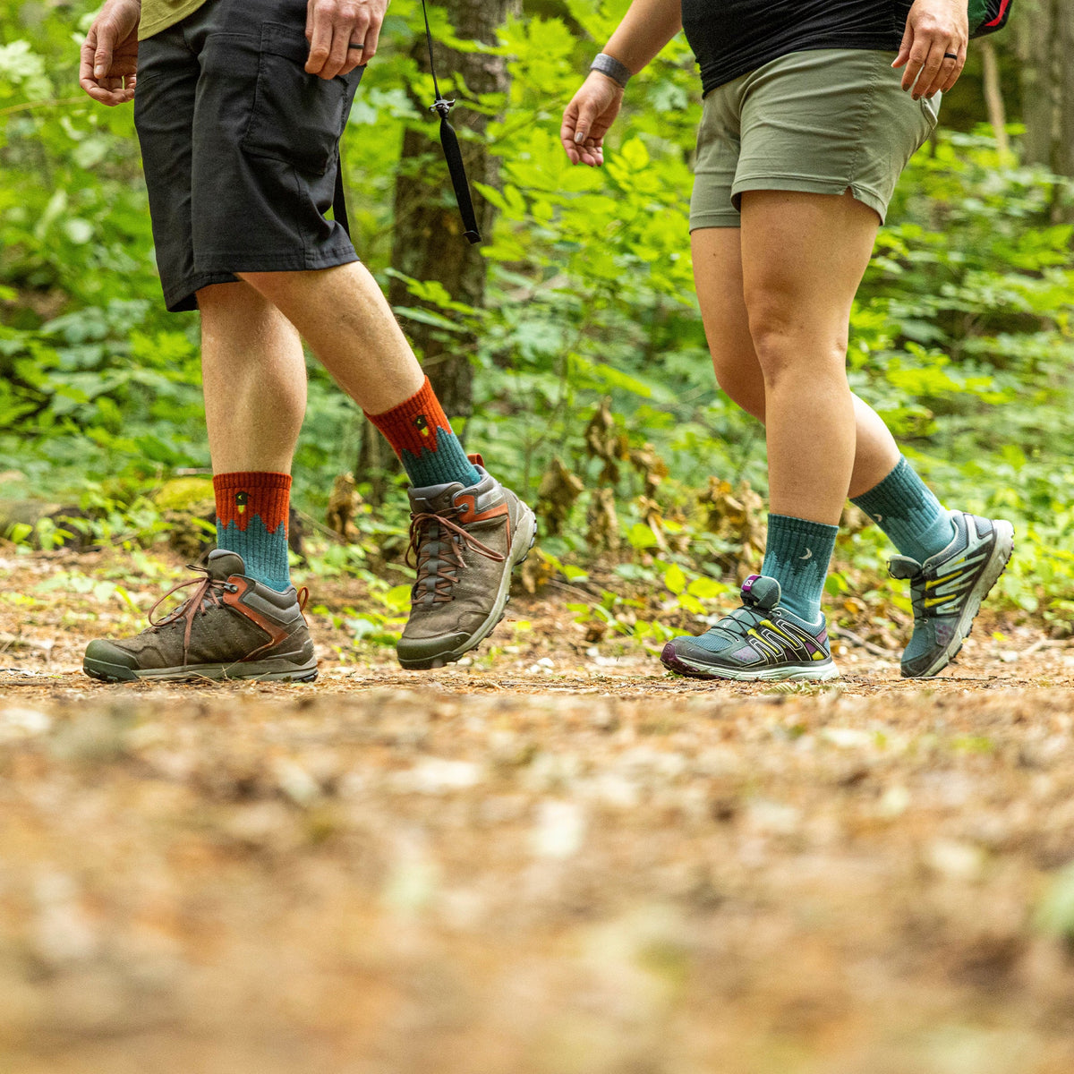 Two people wearing aqua blue crew hiking socks with outdoor shoes on trail.