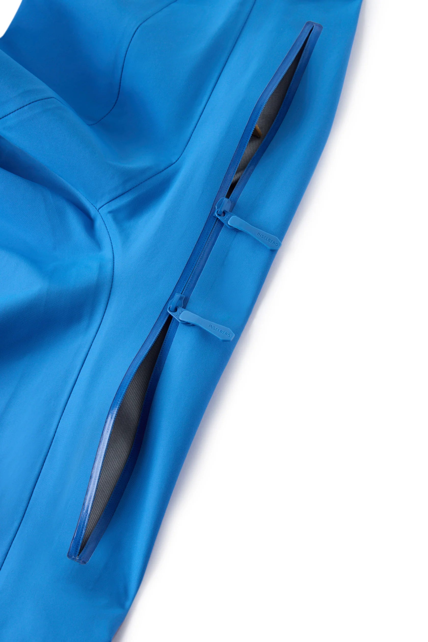 Hooded shell jacket side zipper with blue fabric flap and black zipper guard