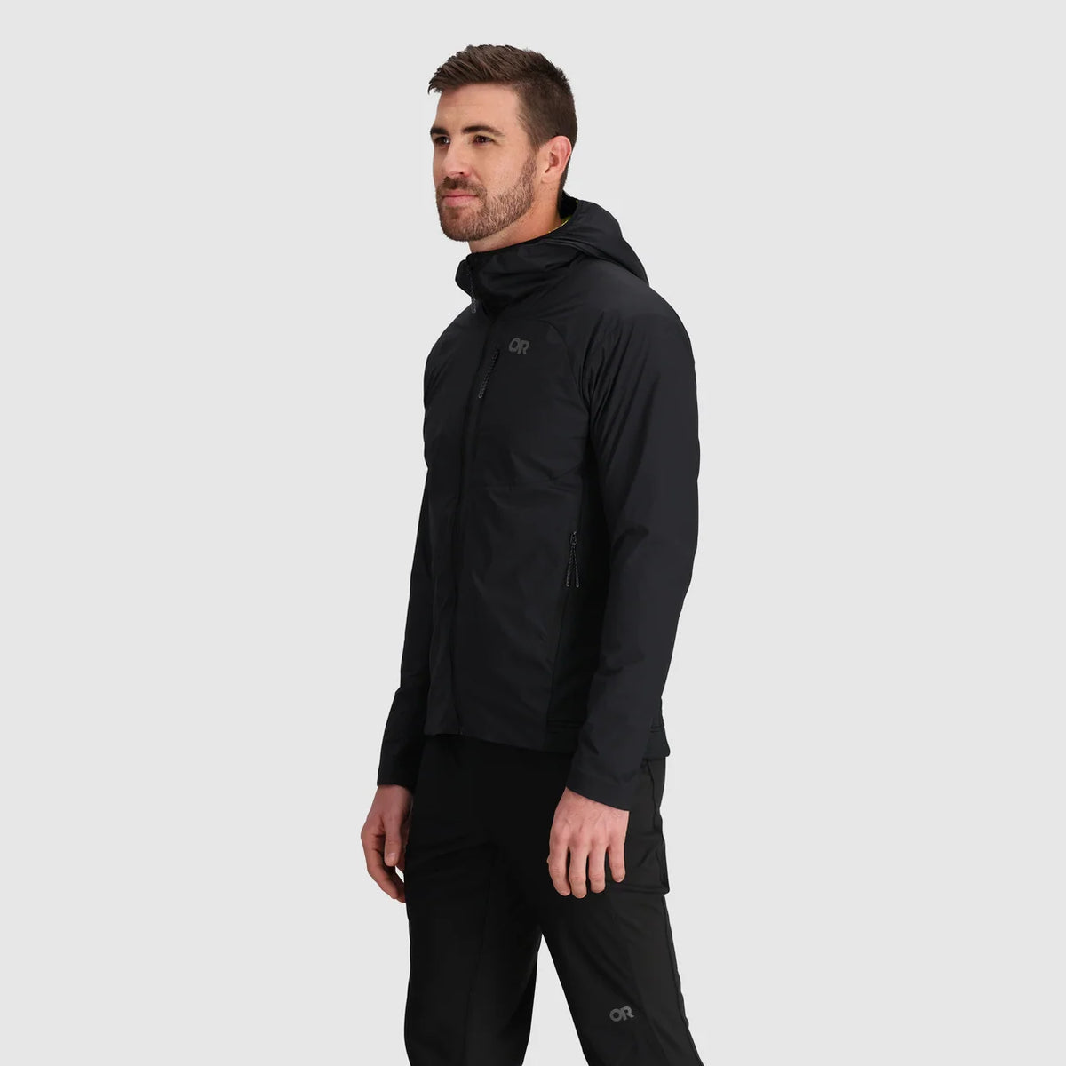 Side view of a man wearing a black hooded jacket with zip pockets