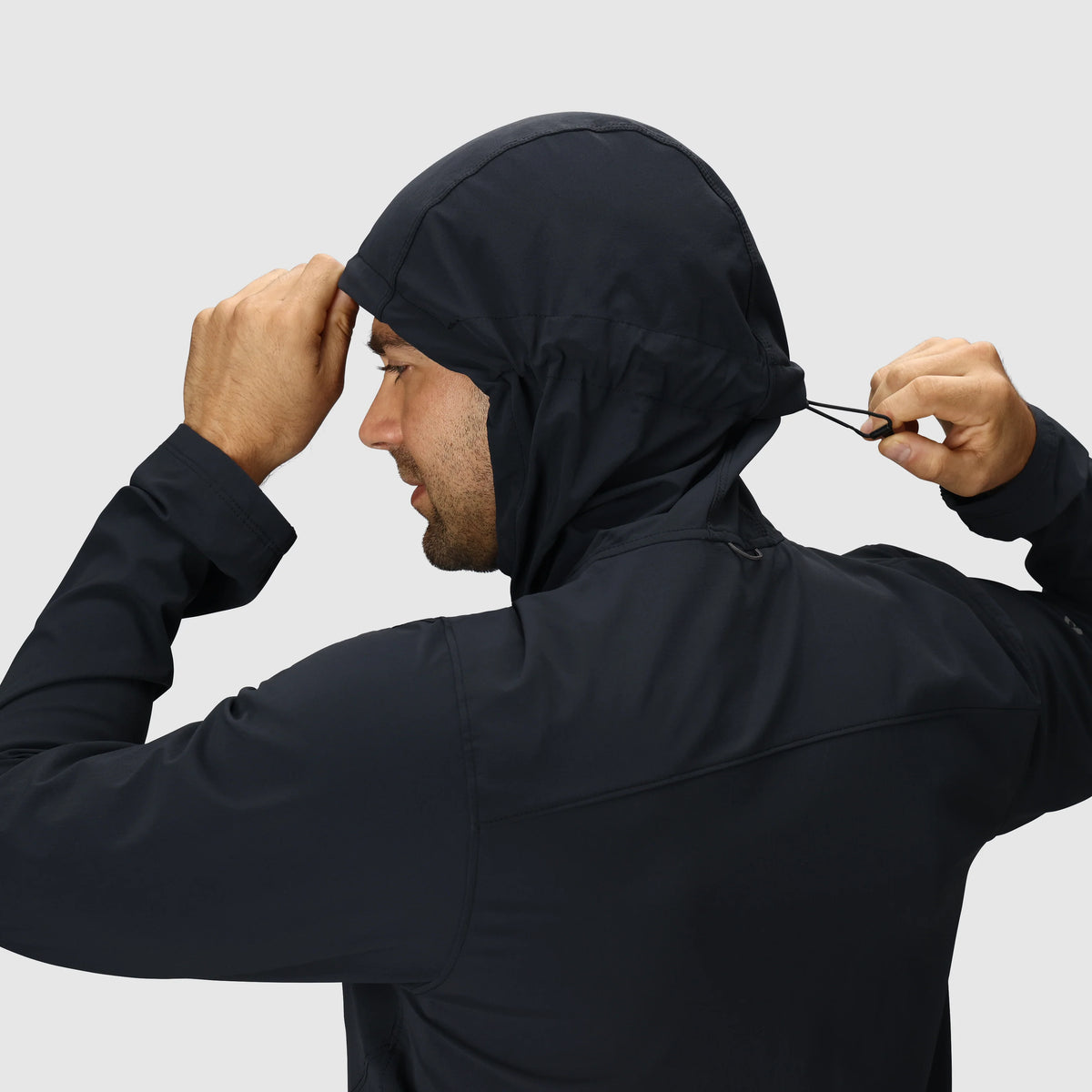 Men's dark softshell jacket with hood cinch cord being adjusted