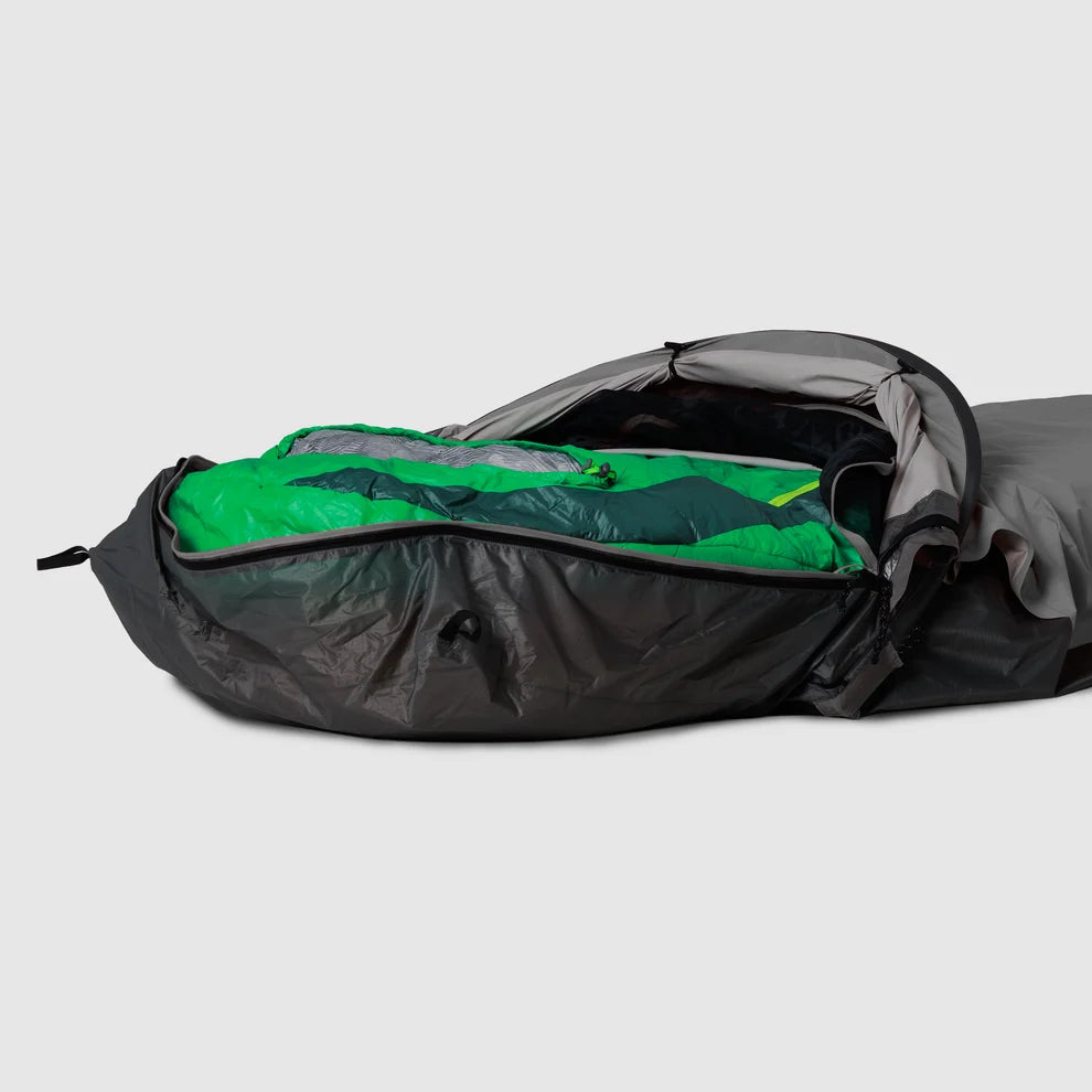 Gray bivy shelter open with a sleeping bag inside