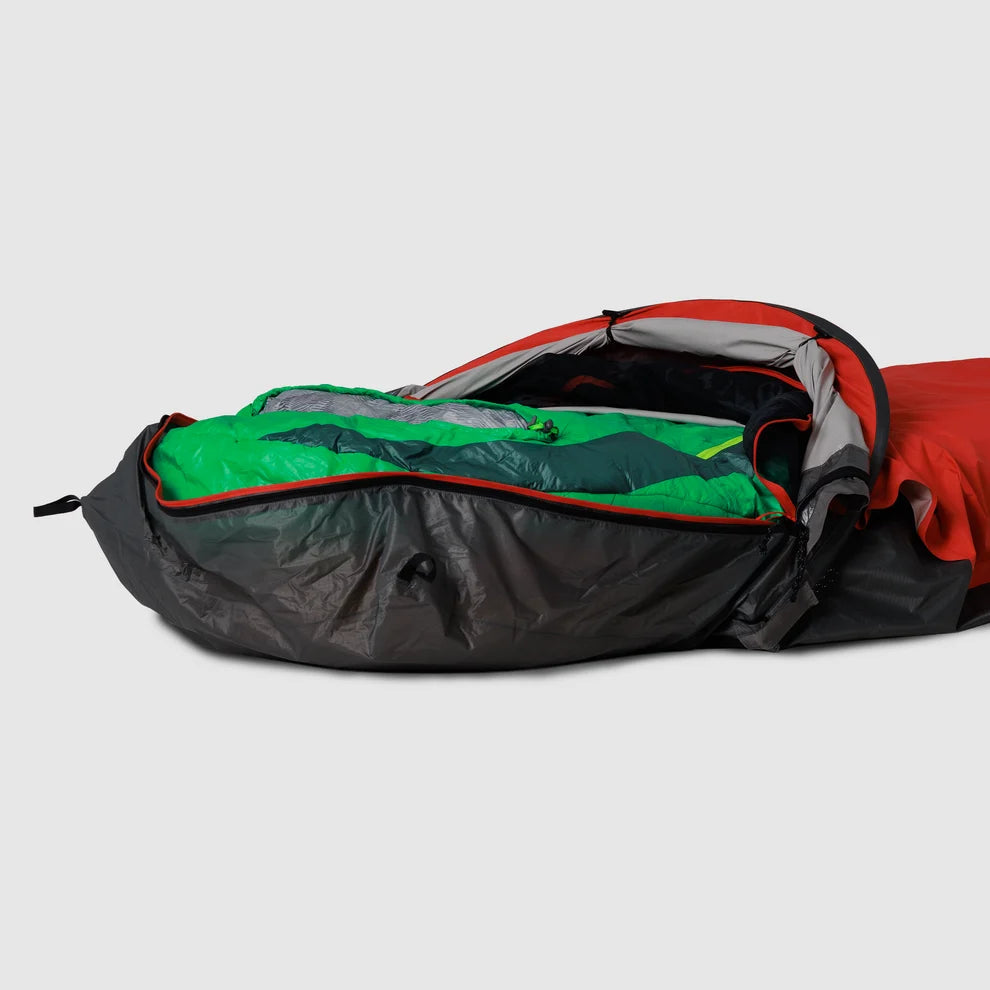 Red bivy shelter open with a sleeping bag inside