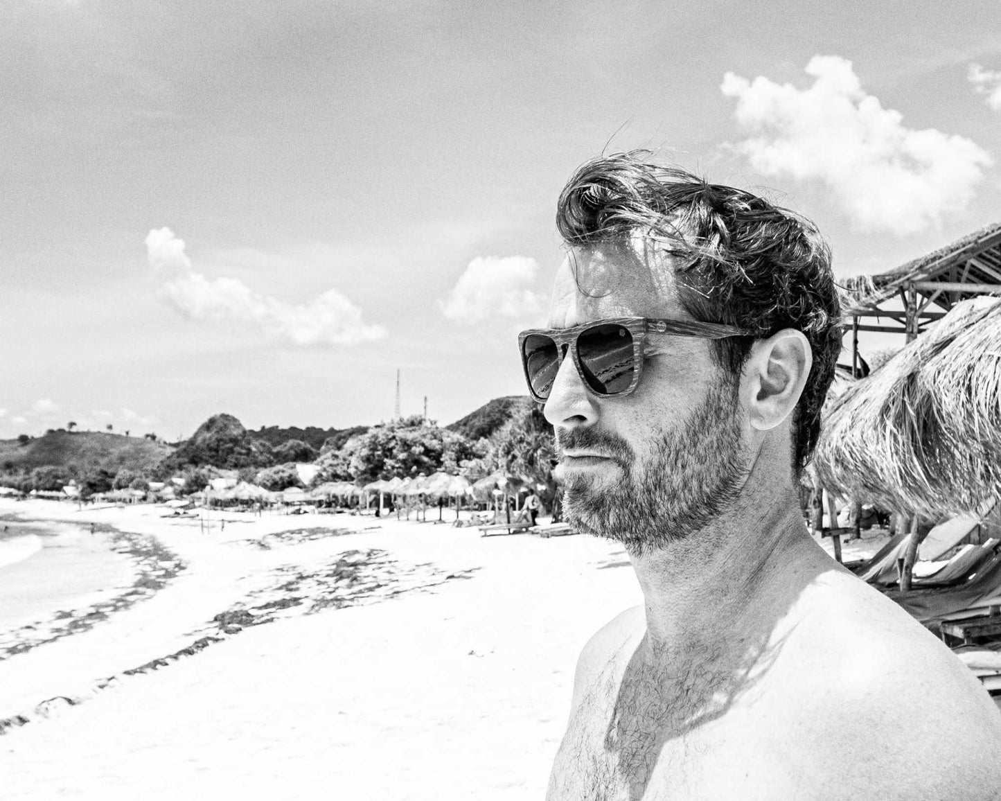 Polarized sunglasses on a person: dark lenses, dark woodgrain frame.