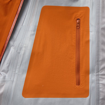 Inner zipped pocket panel on orange rain jacket lining