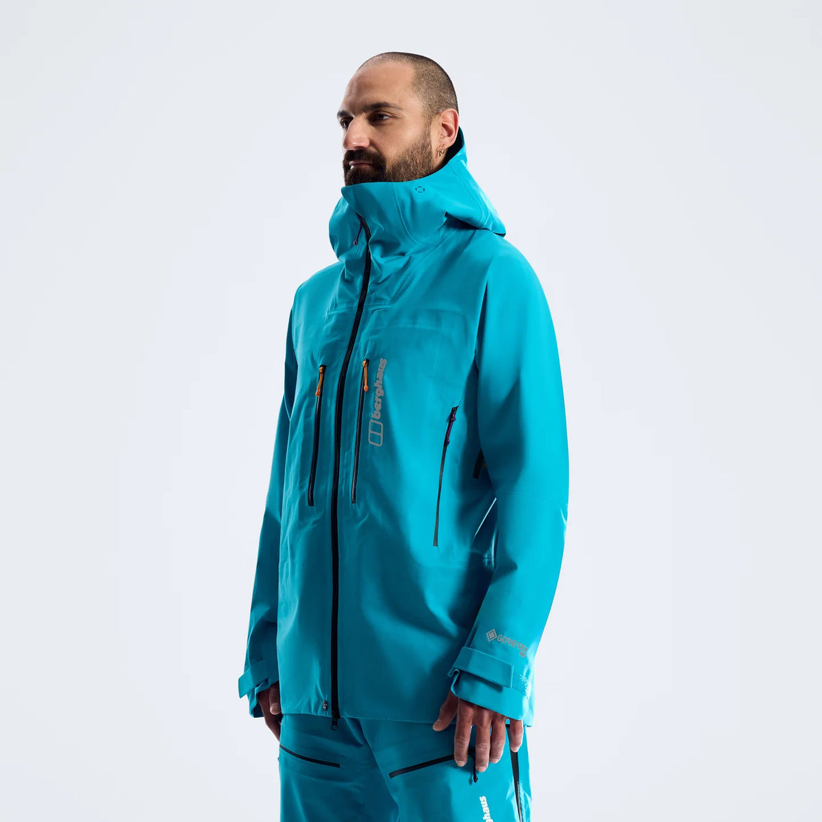 Men's blue waterproof jacket with hood and side pocket zippers, profile view
