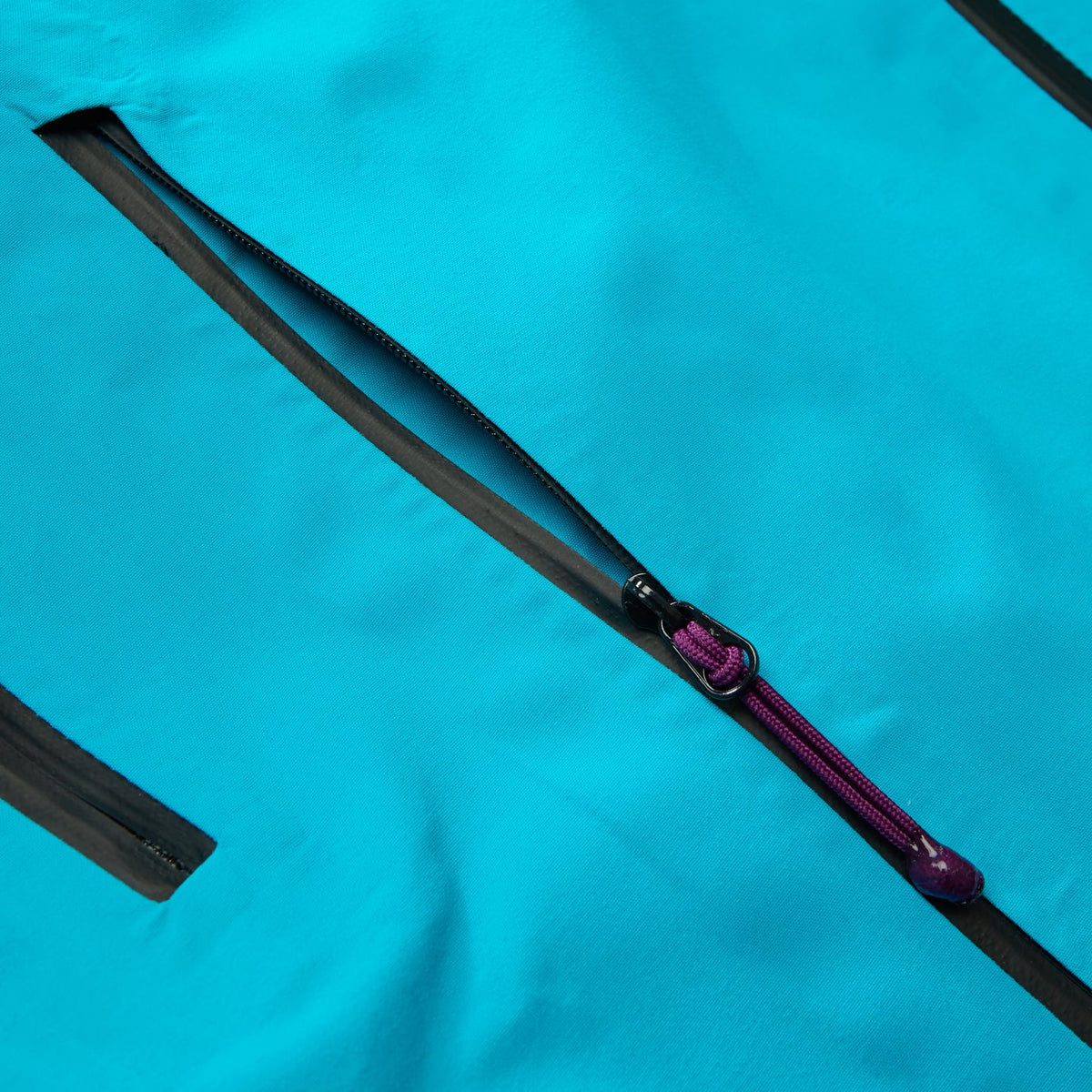 Black trim zipper tape with purple cord pull on blue waterproof jacket