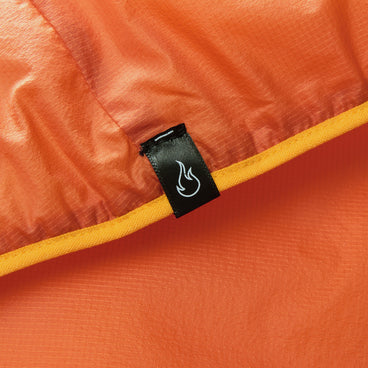 Orange insulated jacket fabric close-up with black brand tag and yellow trim seam