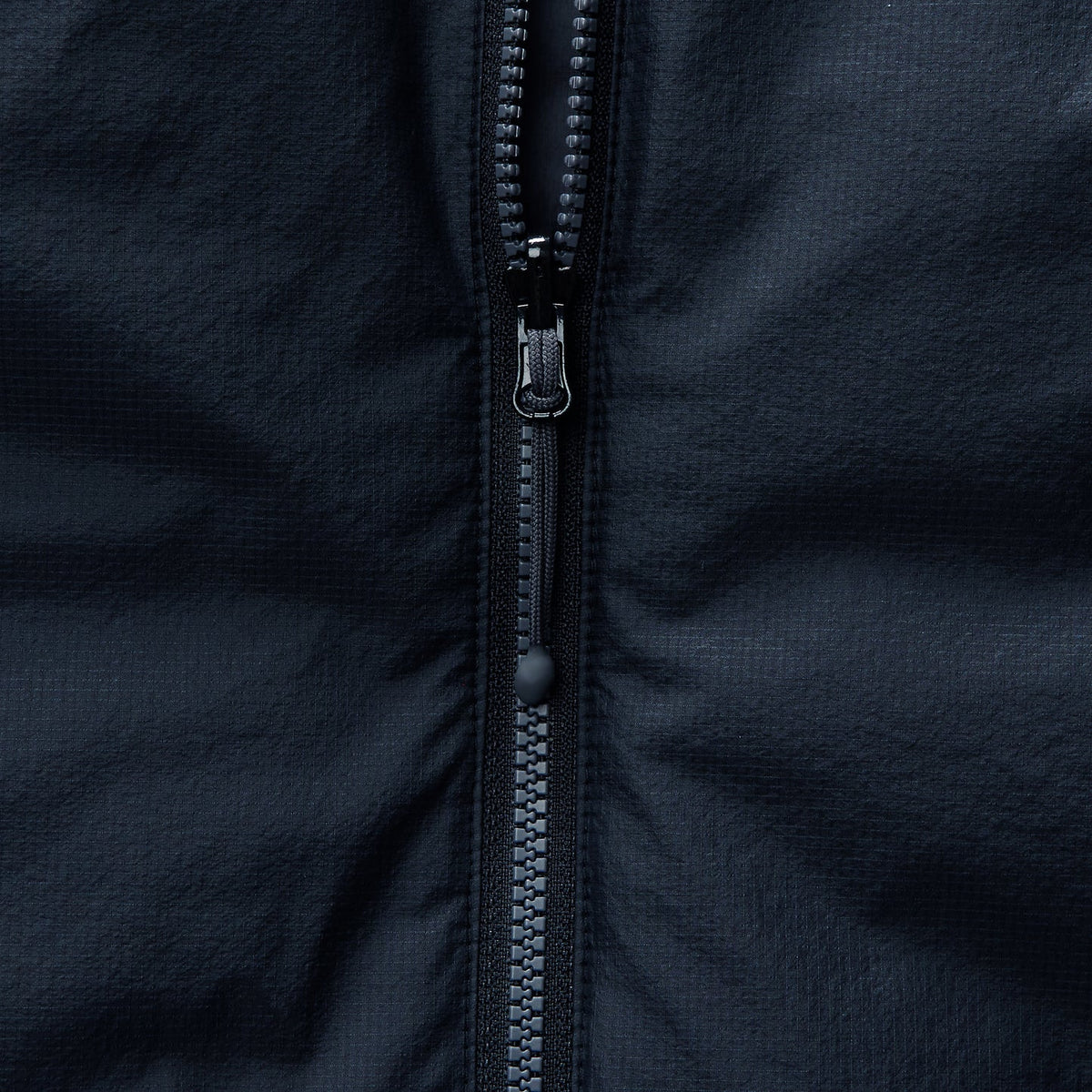 Reversible insulated gilet close-up of full-length zipper teeth and pull.