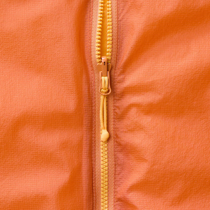 Close-up of orange gilet front zipper with gold-toned pull and teeth