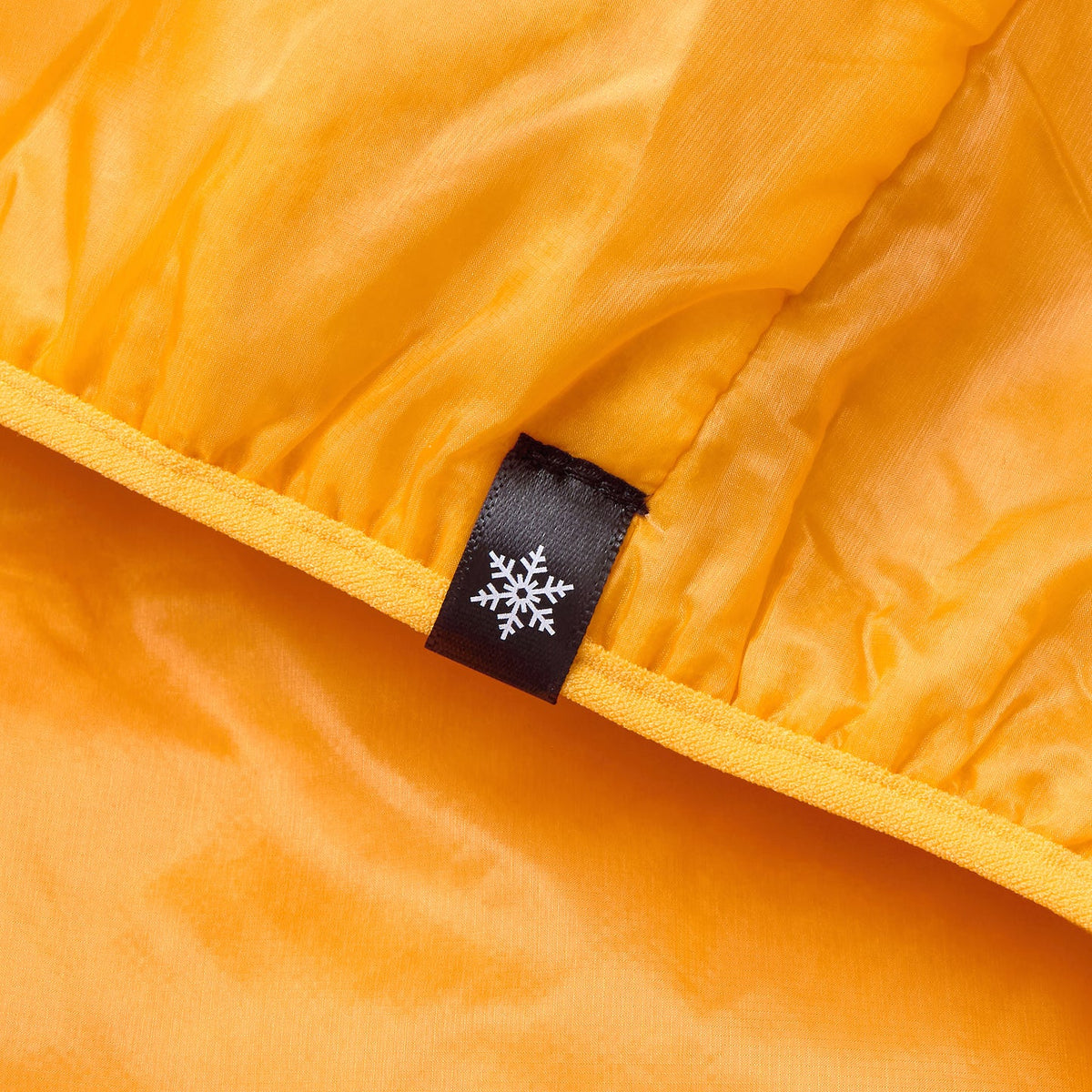 Orange gilet interior with black fabric size label and white snowflake icon on seam