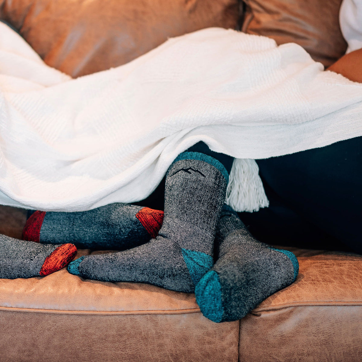 Dark gray merino crew socks with blue heel and toe, resting on a couch