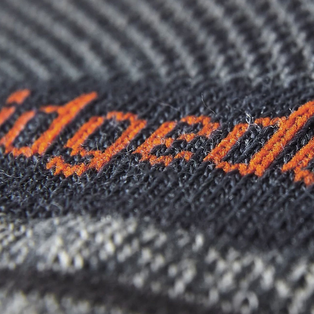 Dark gray merino crew sock knit with orange stitch logo on fabric