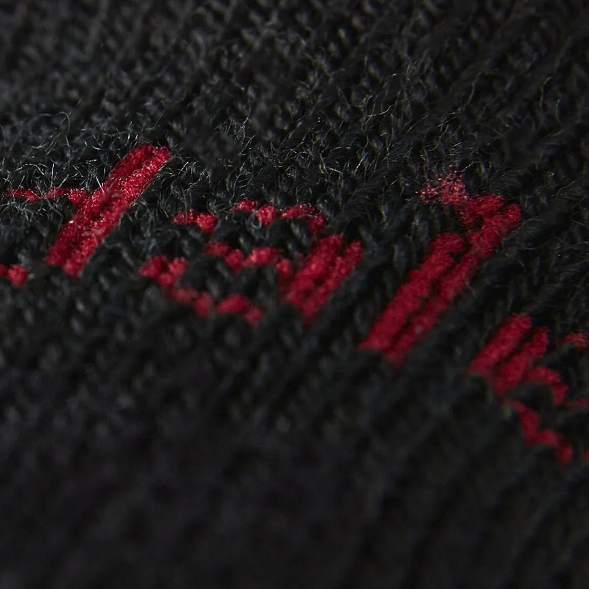 Close-up of black sock knit with red logo lettering