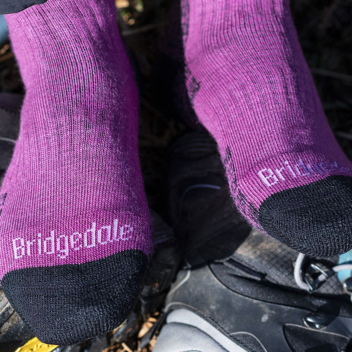 Close-up of berry hiking boot socks with dark toe and heel, logo at ankle cuff