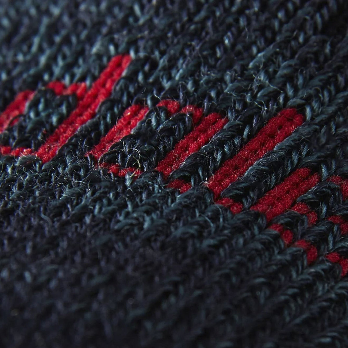 Close-up of merino wool sock knit in navy with bold red stripe accents