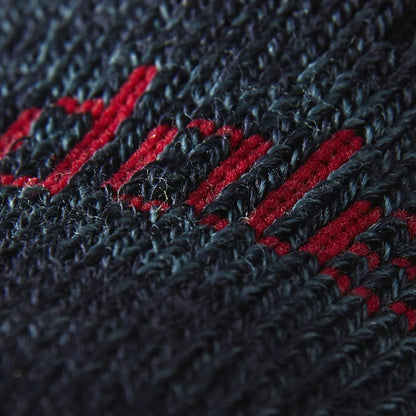 Close-up of merino wool sock knit in navy with bold red stripe accents