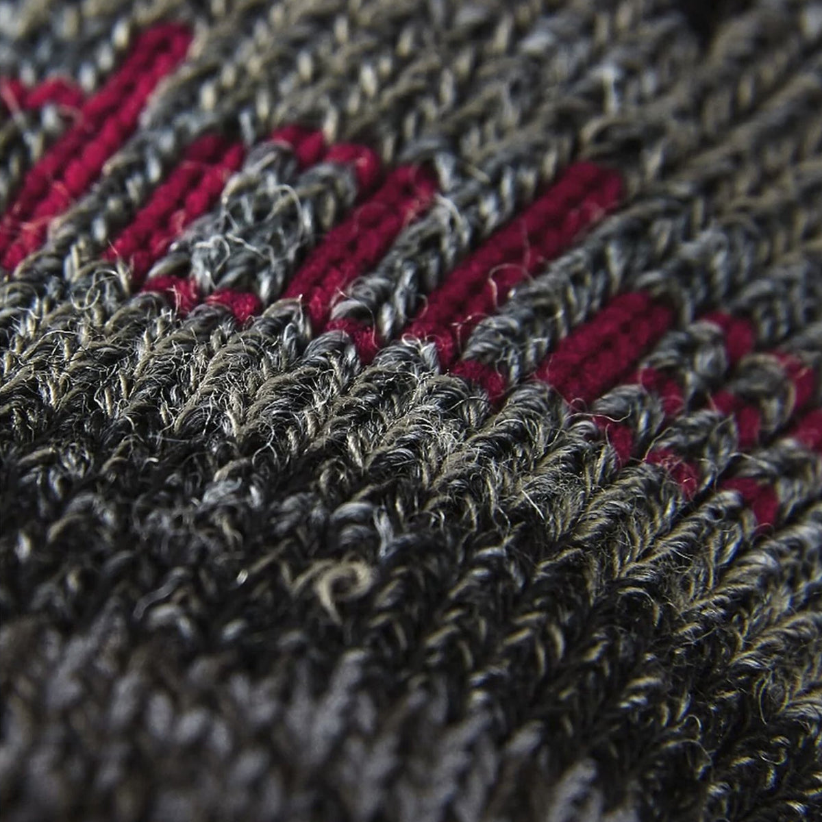 Close-up of textured merino wool sock knit in dark gray with red accent stripes