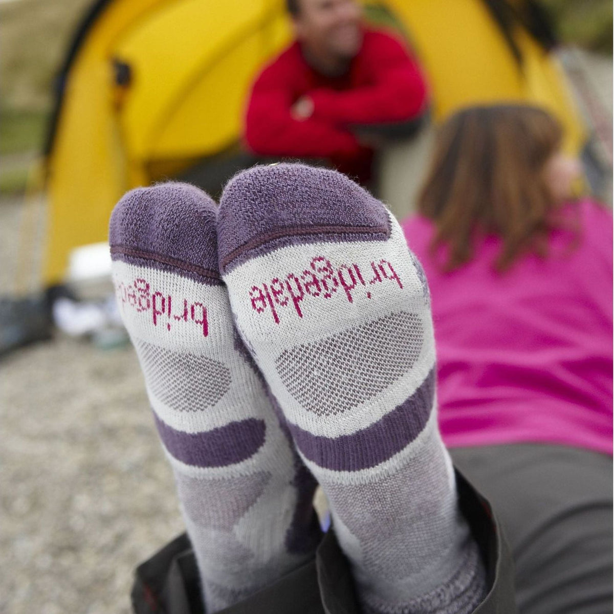 Plum and gray striped hiking boot socks on feet with outdoor clothing.