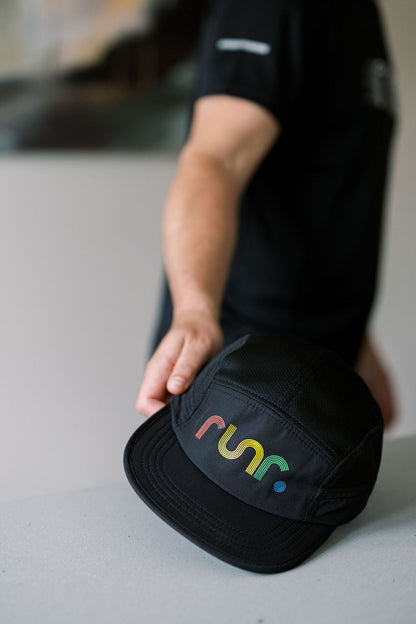Black technical running hat with curved brim and multicolor logo patch on front panel