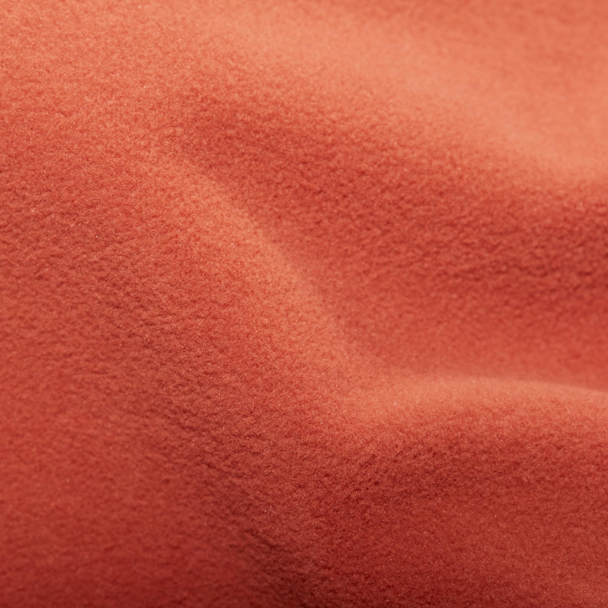 Coral-orange fleece fabric close-up with soft textured pile