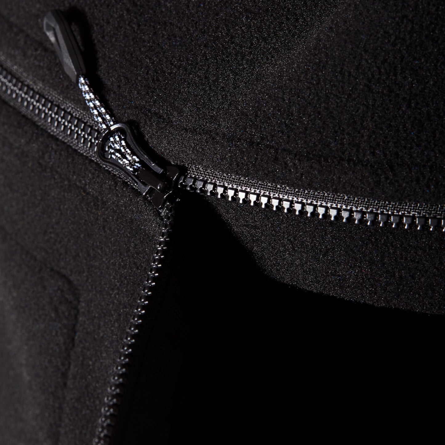 Black fleece jacket zipper track and metal pull on front opening.
