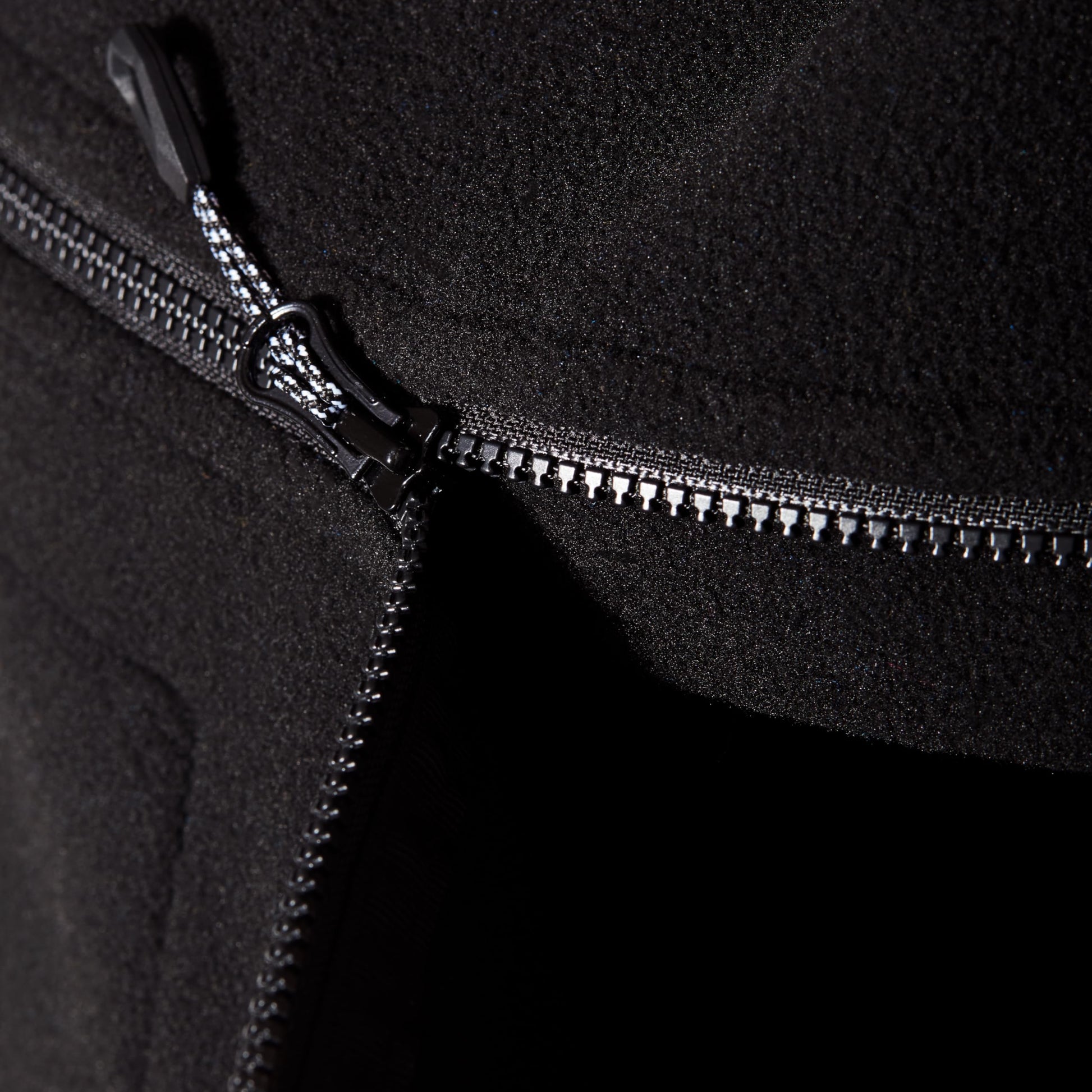 Black fleece jacket zipper track and metal pull close-up