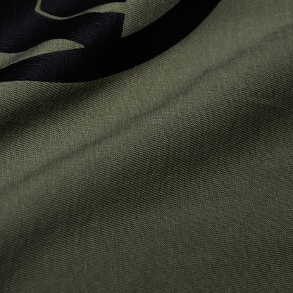 Close-up of olive green T-shirt fabric with part of a black graphic logo