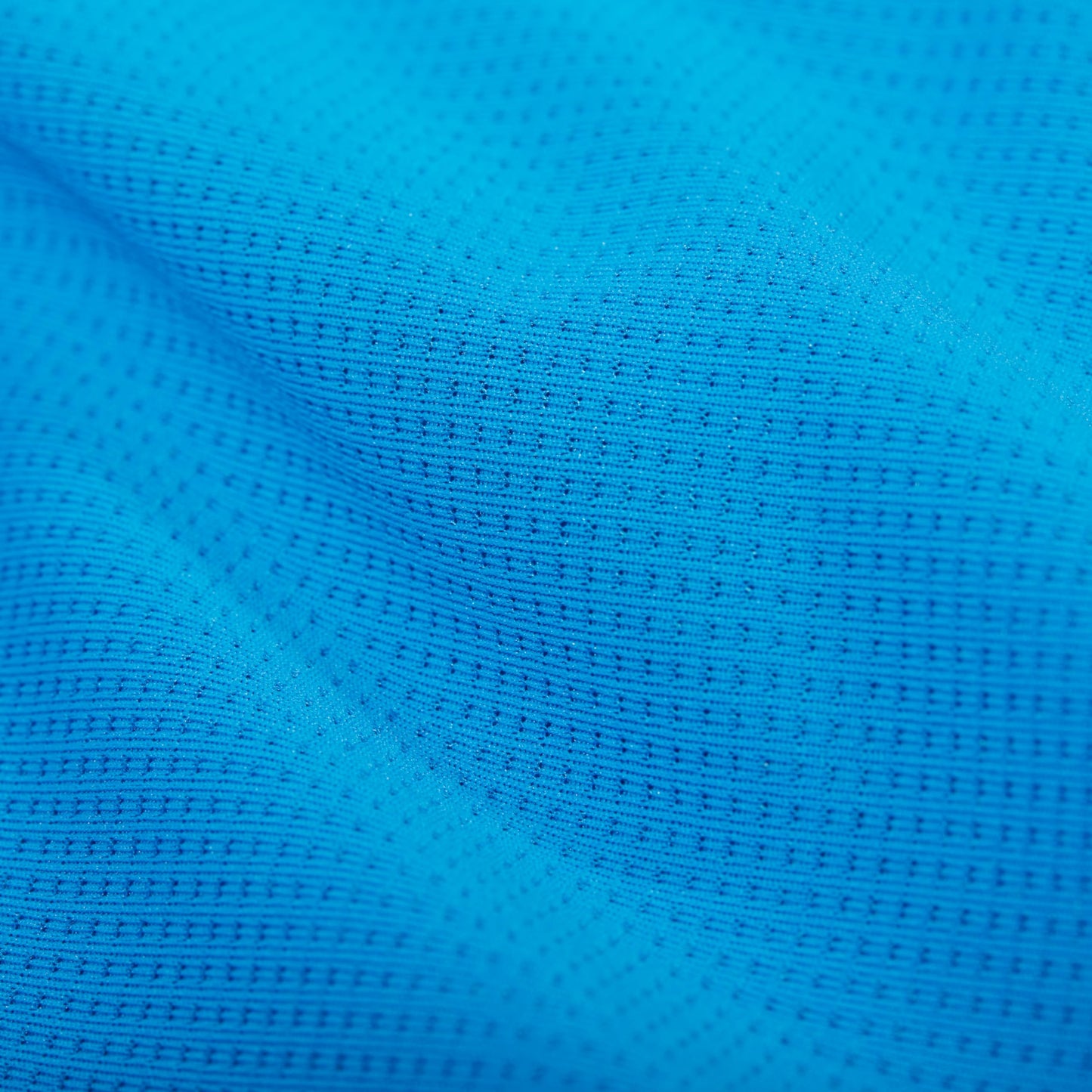 Bright blue knit T-shirt fabric close-up with dotted breathable texture.