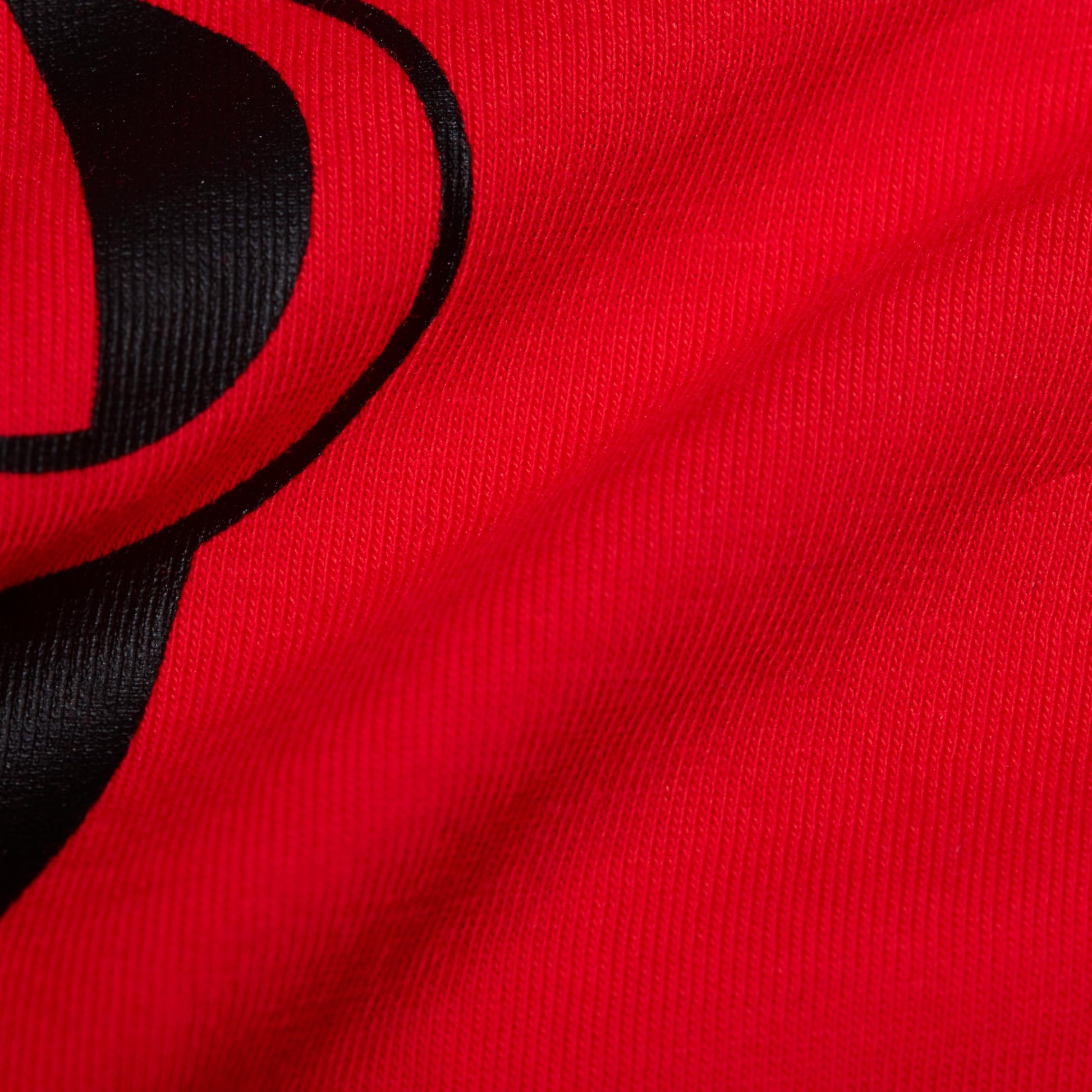 Red T-shirt knit fabric with black graphic logo print close-up