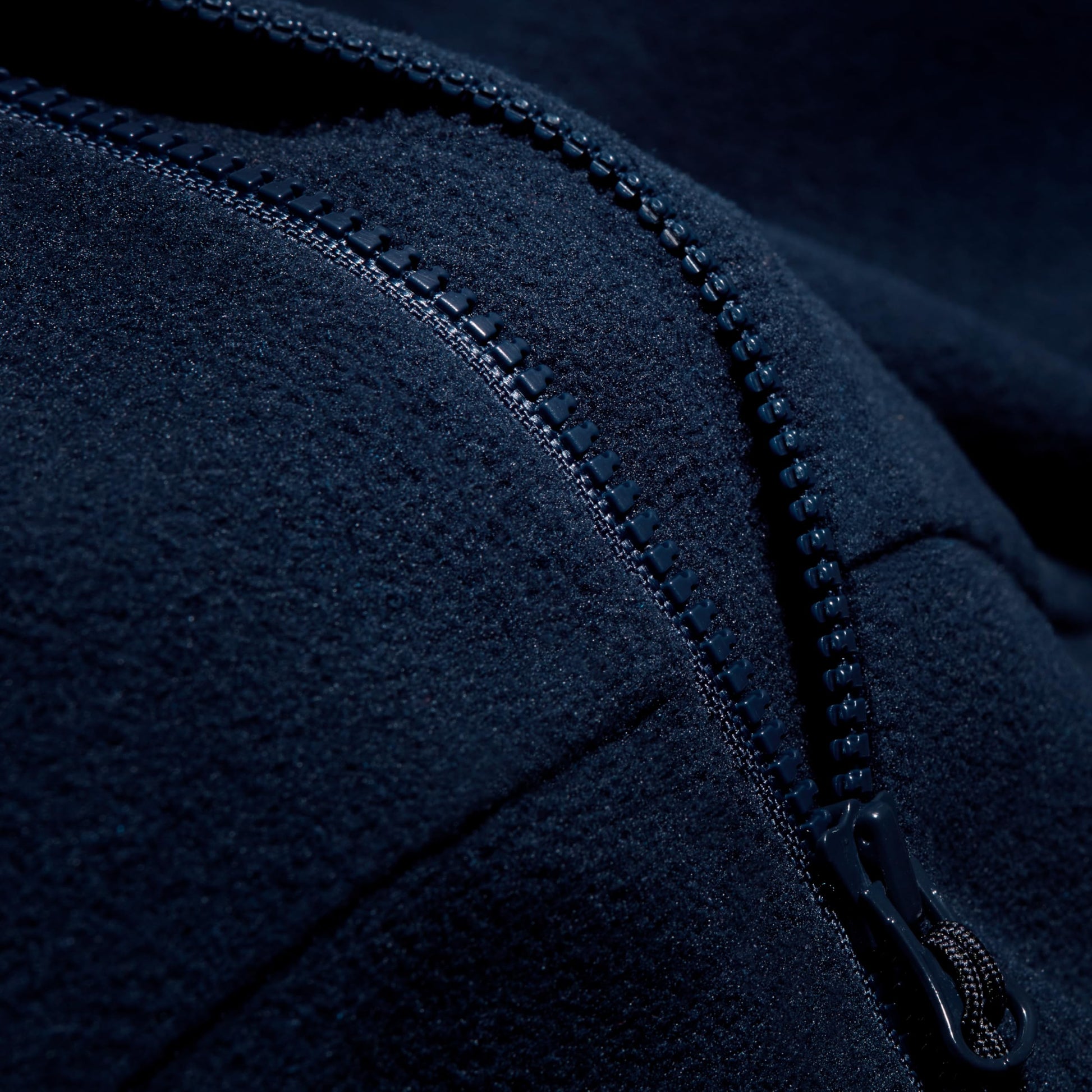 Navy fleece jacket zipper close-up with stitched seam