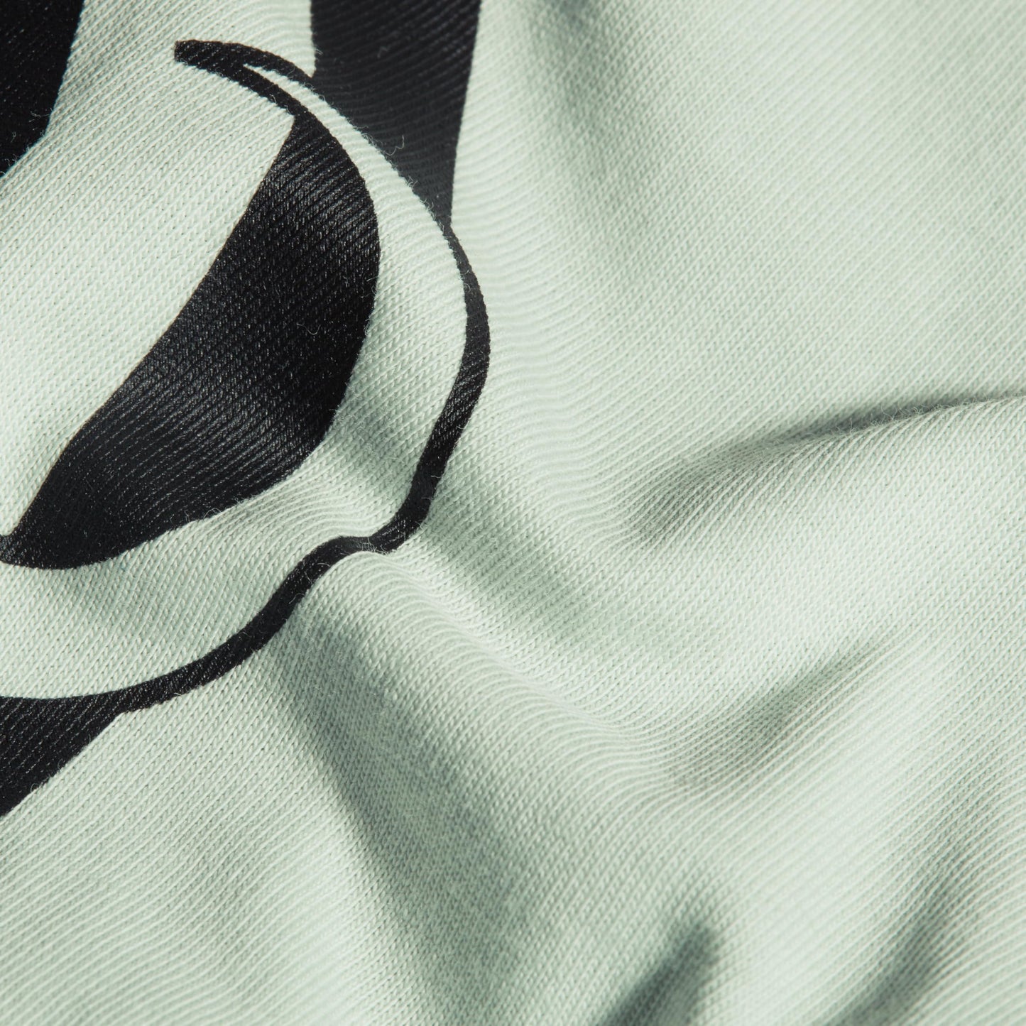 Close-up of mint T-shirt fabric with black graphic logo