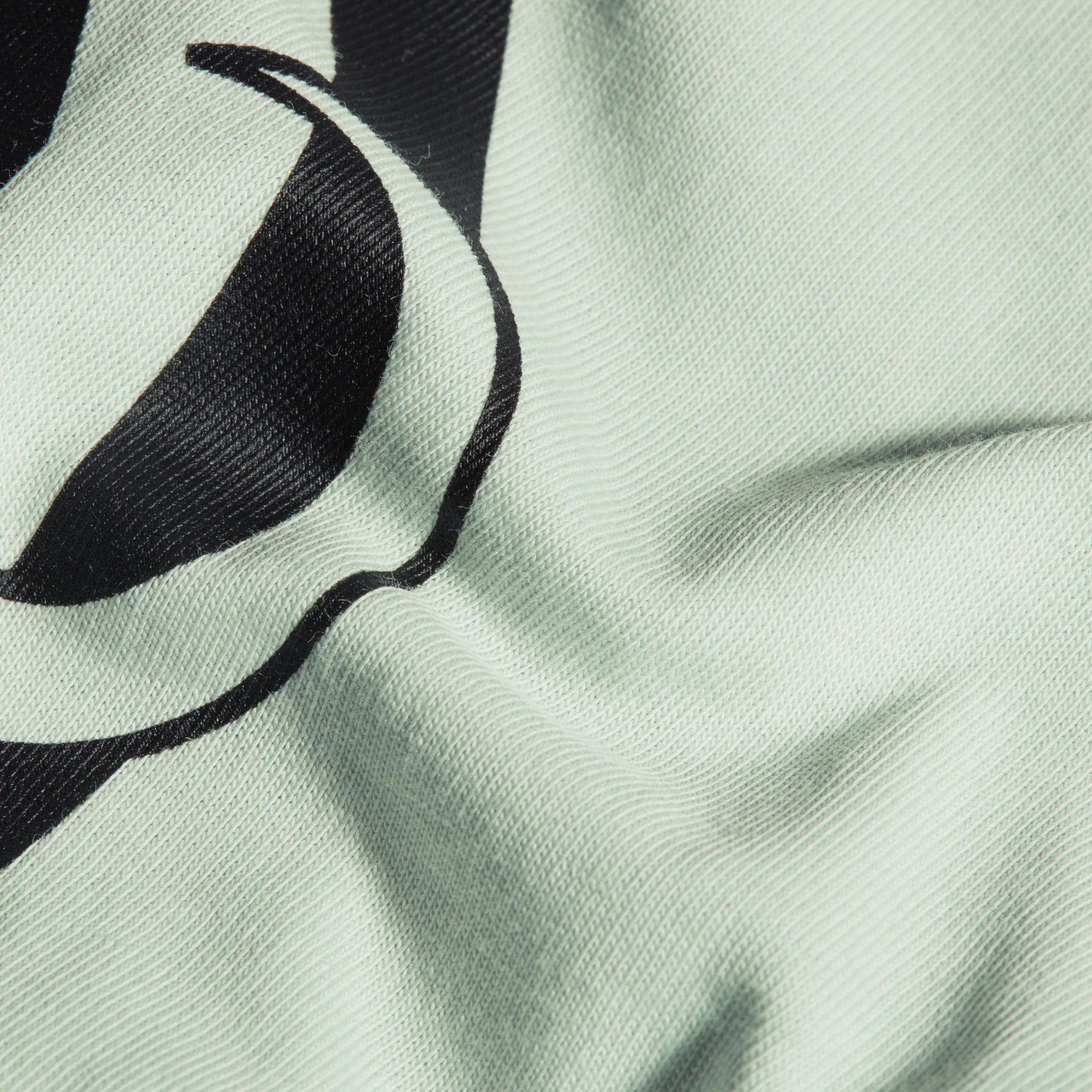 Close-up of mint T-shirt fabric with black graphic logo