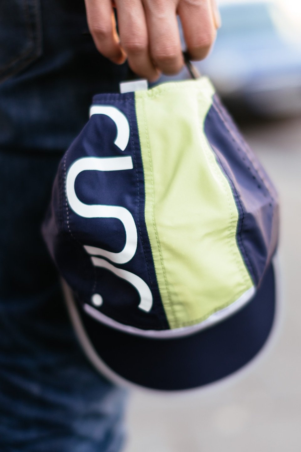 Technical running hat close-up, navy brim with lime panel and large white front graphic