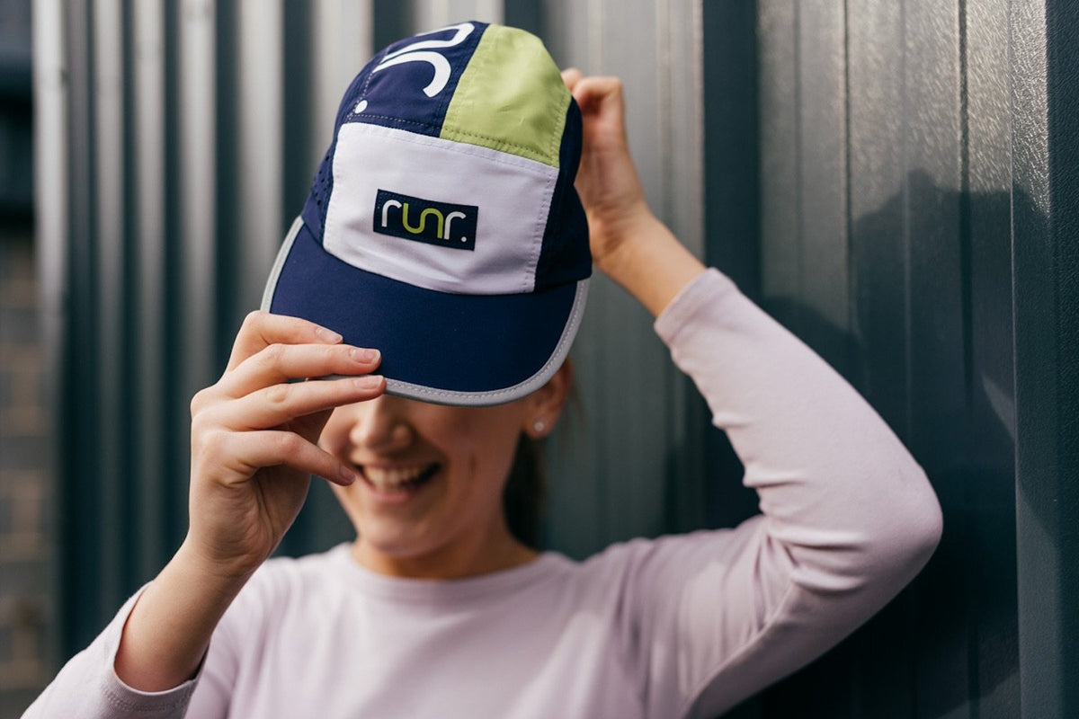 Technical running hat on head, navy brim and lime top with front logo patch
