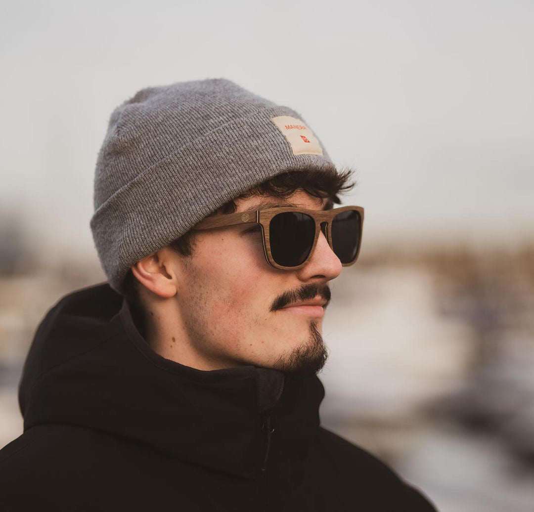 Polarized sunglasses on a person wearing a gray knit beanie and black jacket