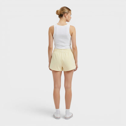 Adidas pale yellow athletic shorts on model with elastic waistband