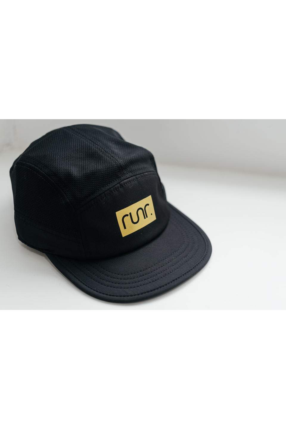Black technical running hat with gold "run." logo on side