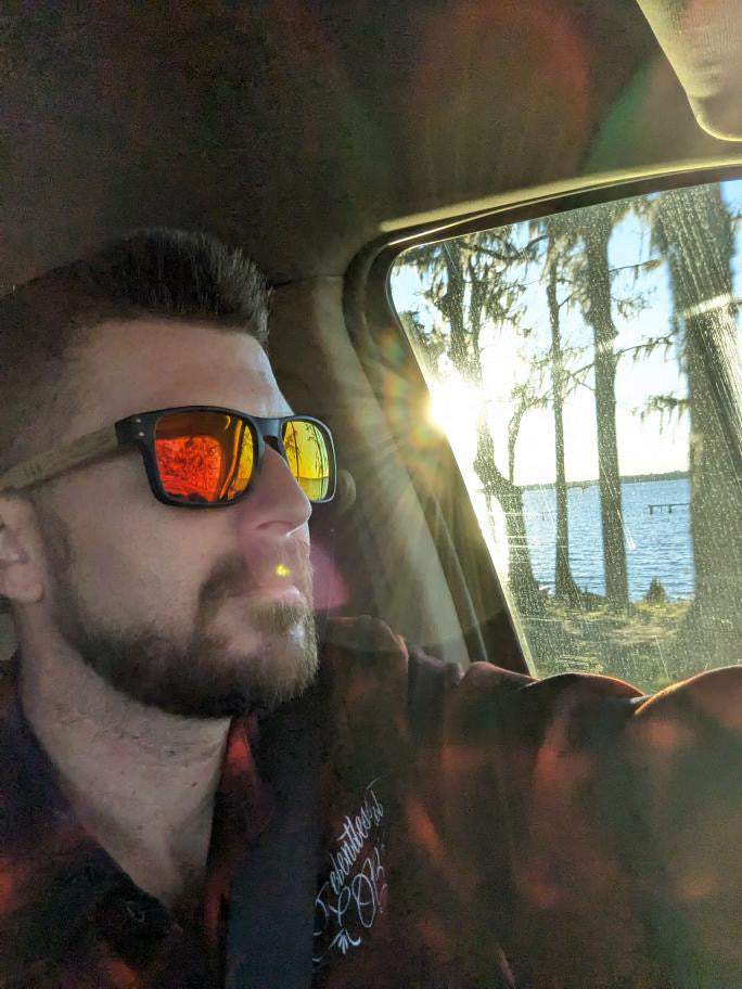 Men’s polarized sunglasses on a wearer: black frame with wood arms, orange mirrored lenses.