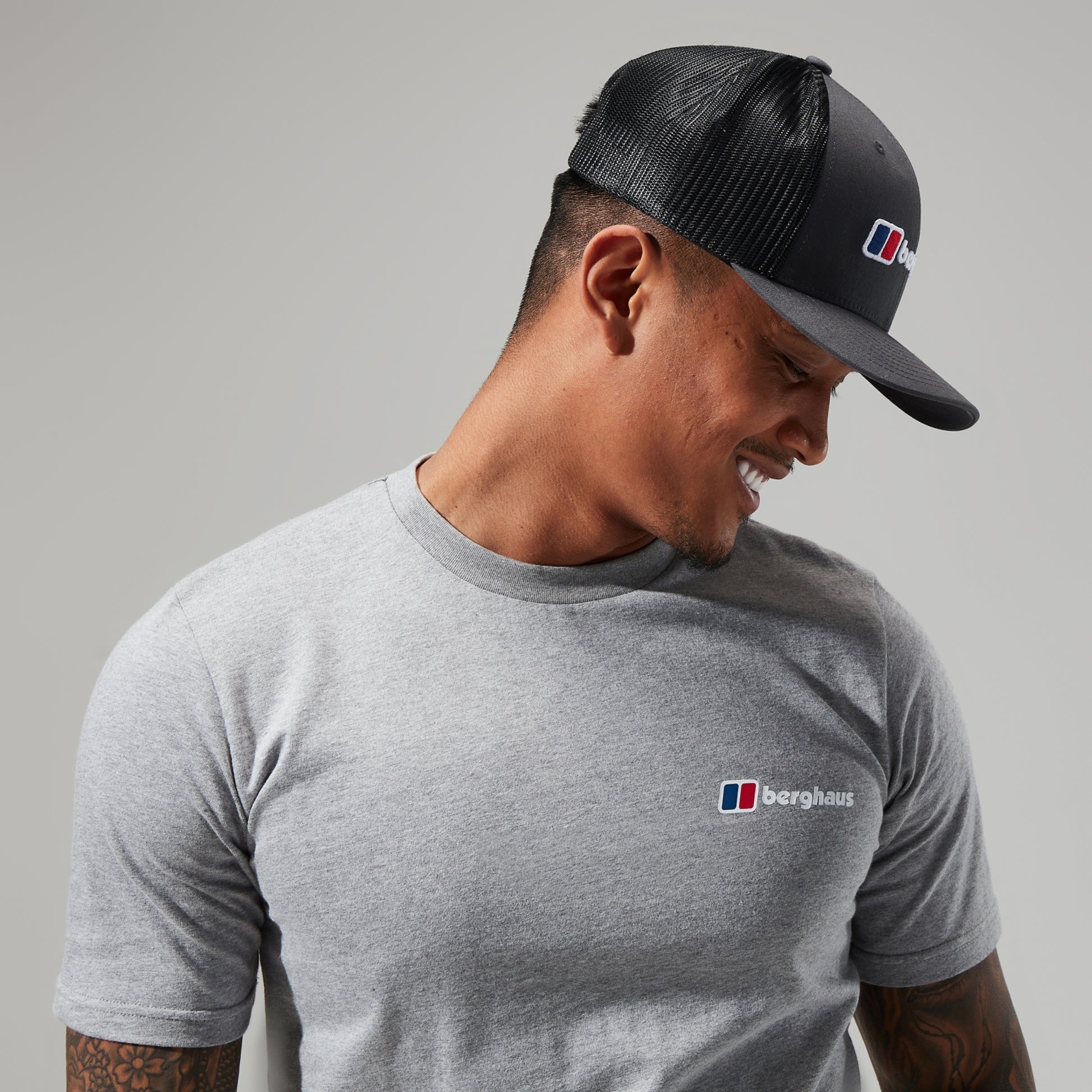 Man wearing a black cap and gray t-shirt with Berghaus logo on a gray background
