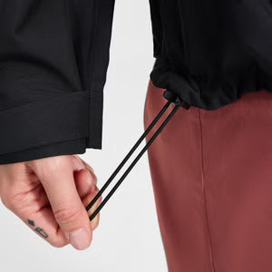 Person wearing a black jacket and maroon pants with a close-up of a drawstring.