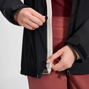 Person adjusting a zipper on a black jacket against a white background