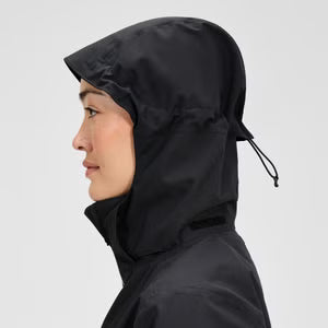 Person wearing a black raincoat with a hood on a light gray background